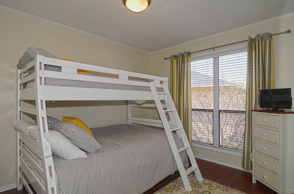 Your cozy bunk room offers comfort for multiple guests with soft striped linens and cheerful yellow accents.