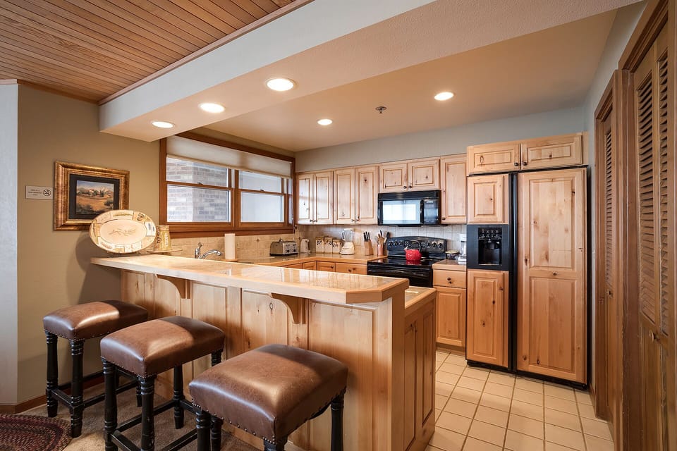 Your fully equipped kitchen awaits with warm wood cabinetry, granite counters, and a welcoming breakfast bar perfect for morning coffee.