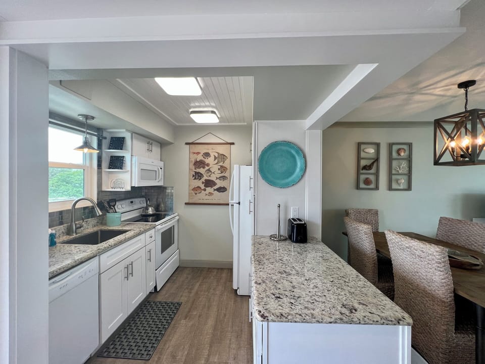 Your spacious kitchen features granite countertops, modern appliances, and coastal decor that creates the perfect setting for preparing memorable meals.