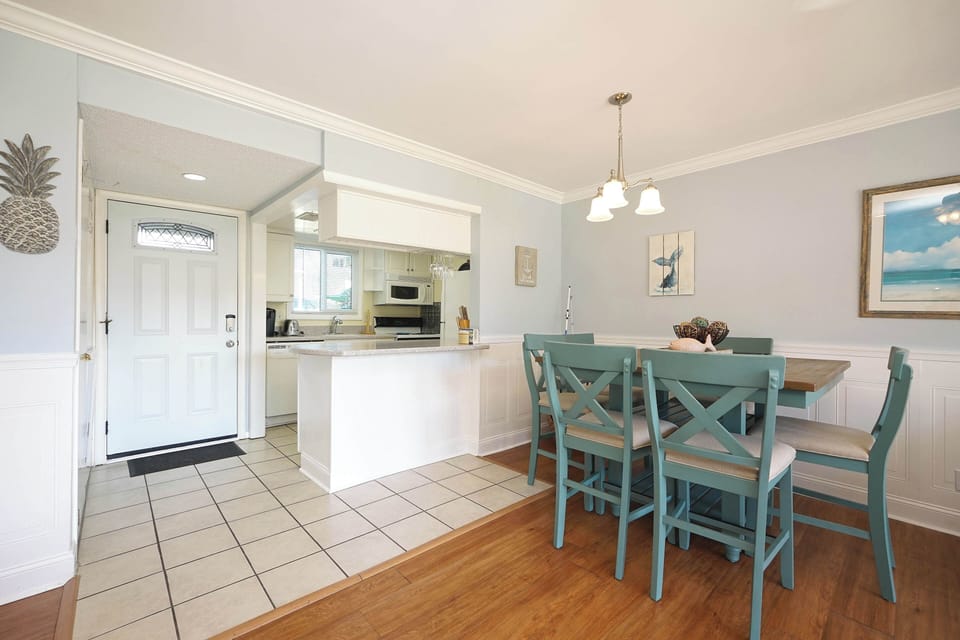 Your open-concept kitchen and dining area welcomes you with coastal charm—turquoise chairs and beach artwork create the perfect setting for memorable meals.