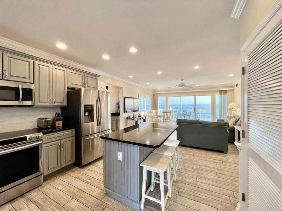 Your fully equipped kitchen flows seamlessly into the living space, where panoramic ocean views create the perfect backdrop for cooking and relaxing.