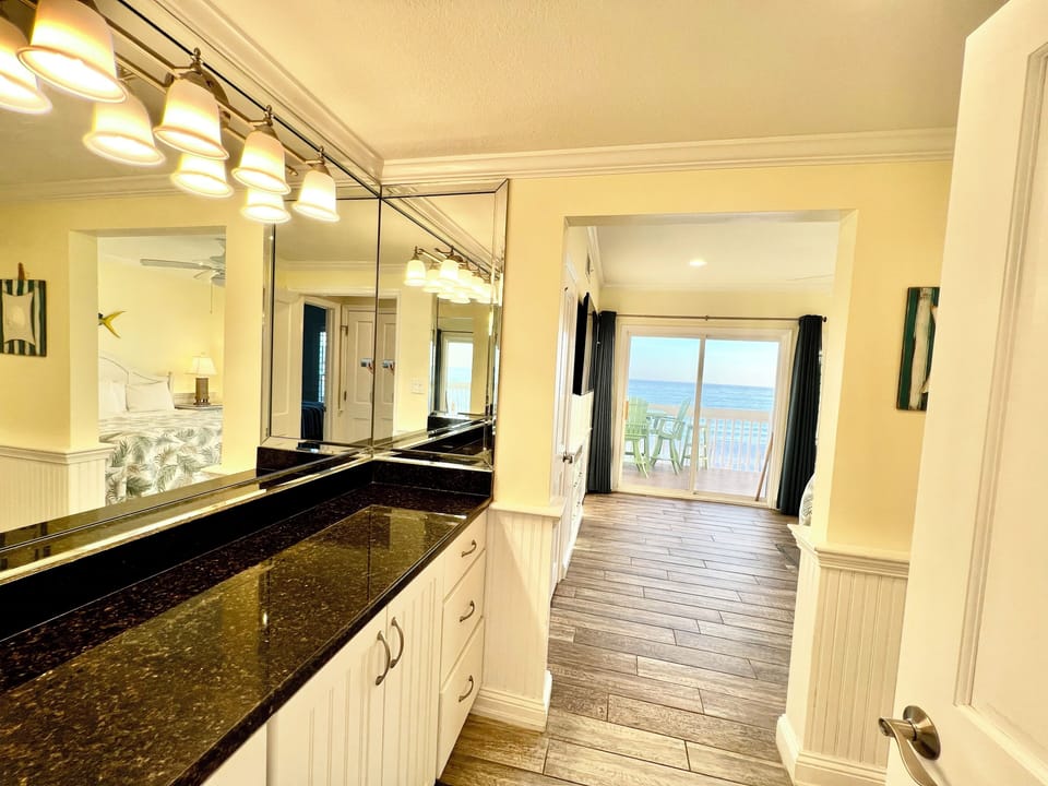 Start your mornings in this elegant bathroom with granite counters and warm lighting, then step onto your private balcony for breathtaking ocean views.