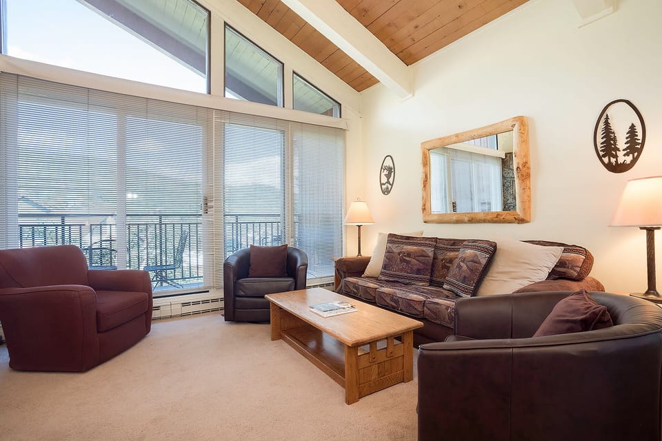 Sink into comfortable leather seating while natural light fills your cozy living space through floor-to-ceiling windows.