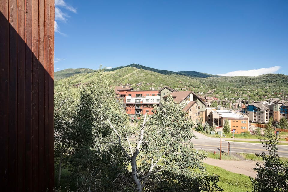 Mountain town setting with green hillsides and residential buildings visible from the property location.