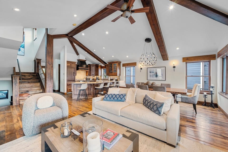 Step into your spacious open-concept retreat where soaring vaulted ceilings with rustic beams create an airy, welcoming atmosphere. Relax in the living area or gather around the dining table while natural light pours in.