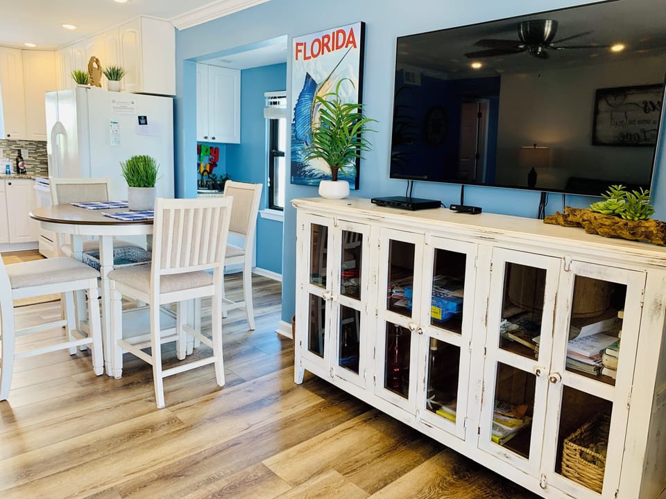 Relax in your open-concept living space with coastal blue walls, white furnishings, and vintage Florida charm throughout.