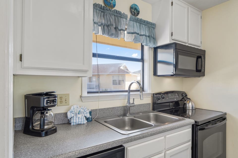 Your kitchen awaits with everything you need: coffee maker for slow mornings, full stove and microwave, plus a bright window that brings in natural light while you cook.