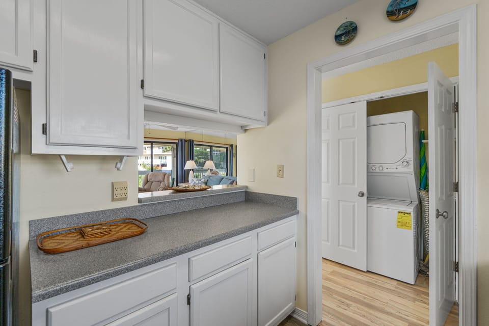 Your bright kitchen features clean countertops and classic white cabinetry, with a convenient pass-through to the living area and in-unit washer and dryer just steps away.