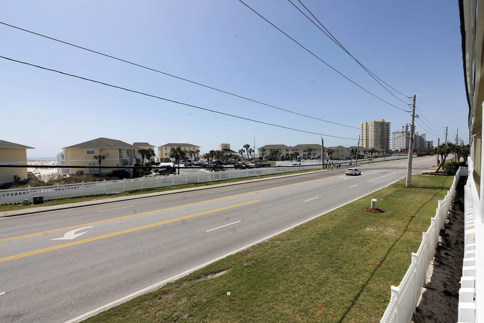Main coastal road with beach access, residential homes, and high-rise buildings visible in the surrounding area.