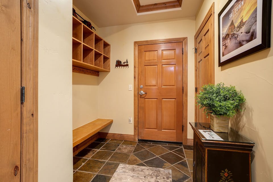 Welcoming entryway with natural light from a skylight, warm wood tones, built-in storage cubbies, and slate tile flooring—perfect for kicking off your snow boots after a mountain adventure.