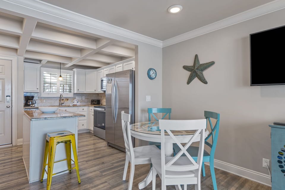 A bright, coastal-inspired space where the kitchen flows seamlessly into your dining area. The starfish accent and beachy touches set a relaxed tone for vacation meals together.