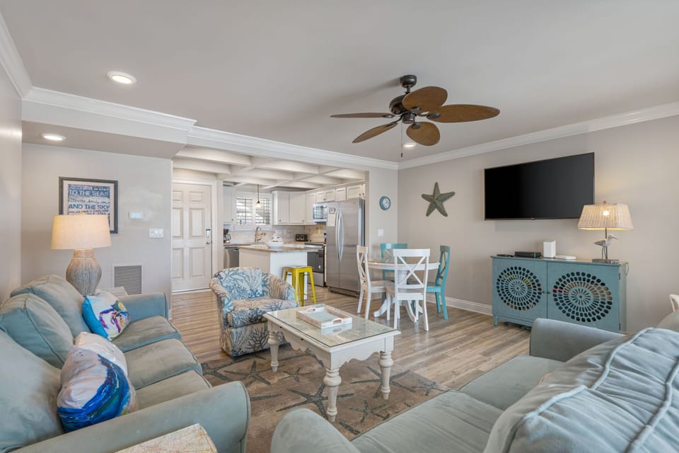 Settle into your coastal retreat, where soft blues and sandy neutrals invite relaxation. Plush seating, a breezy ceiling fan, and an open layout make this your perfect home base for beach days and sunset evenings.