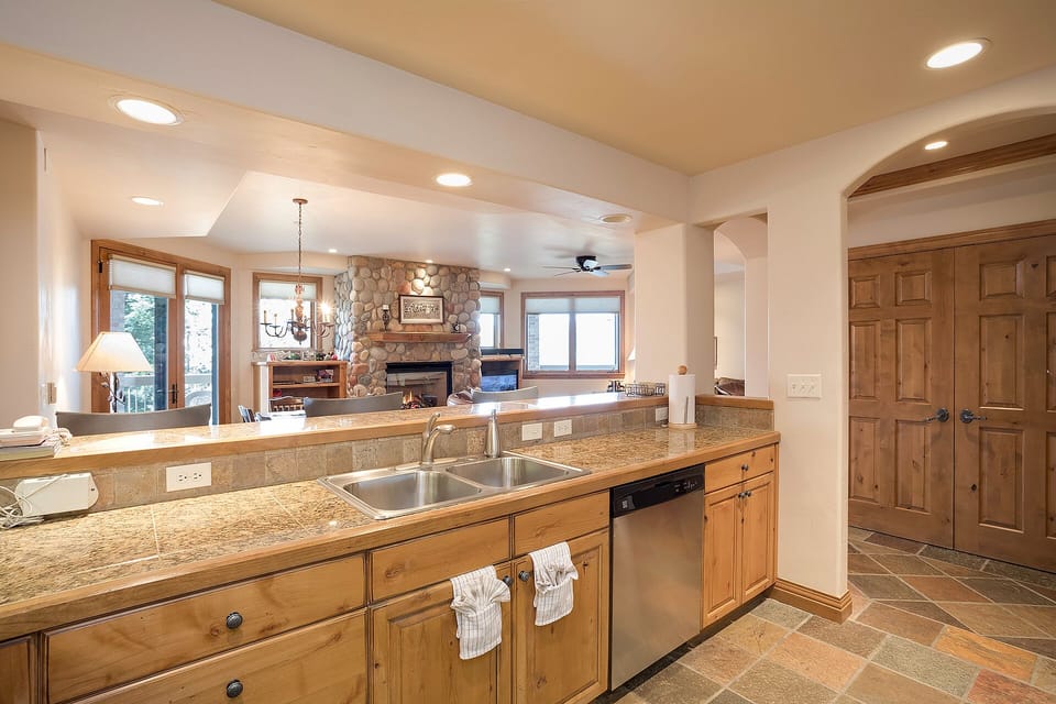 Your gourmet kitchen opens to a cozy living area with stone fireplace, creating the perfect gathering space for memorable meals.