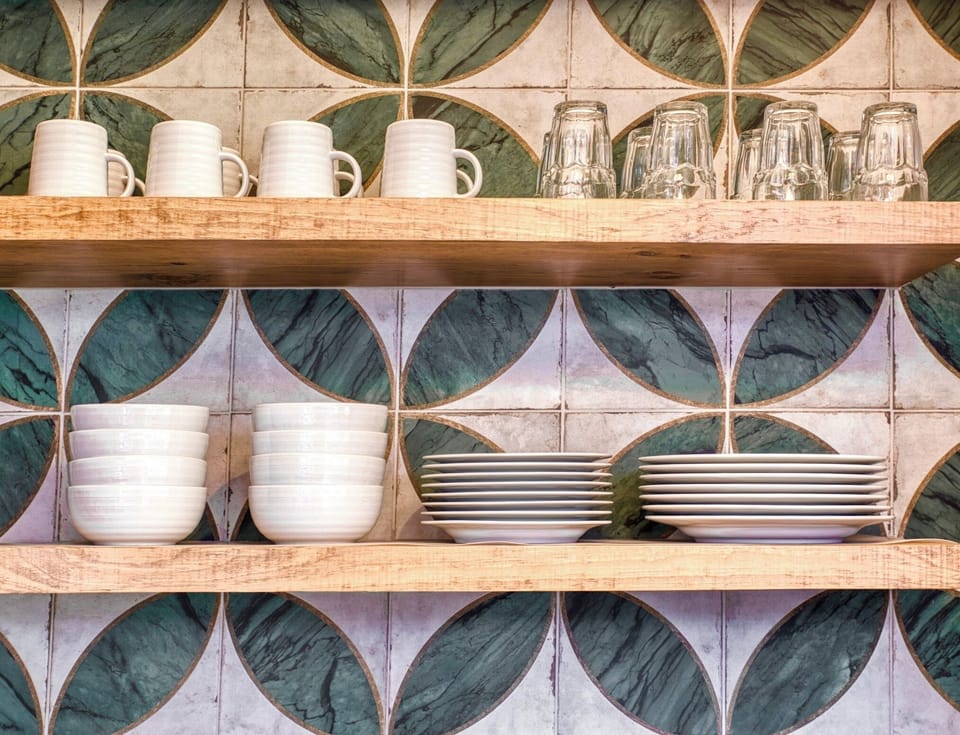 Quality dishware, on open wood shelving against a gorgeous tile backdrop