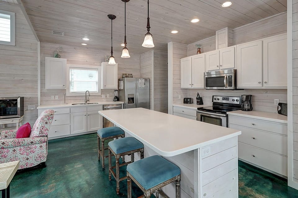 Your bright kitchen features modern appliances, a spacious island with seating, and charming shiplap walls that create a cozy coastal vibe.