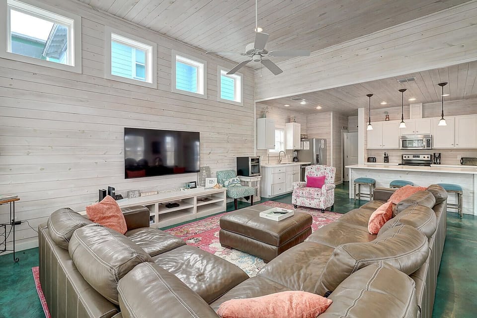 Relax in your spacious open-concept living area with plush leather seating, modern kitchen, and coastal charm throughout.