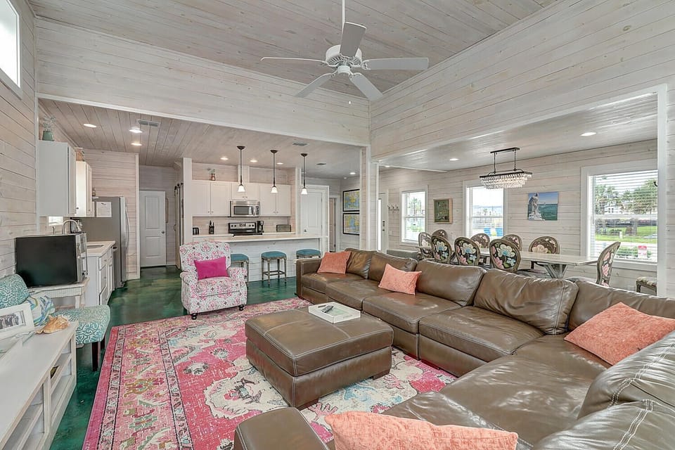Relax in your spacious living area with plush leather sectional, overhead fan, and open concept flow to the modern kitchen.