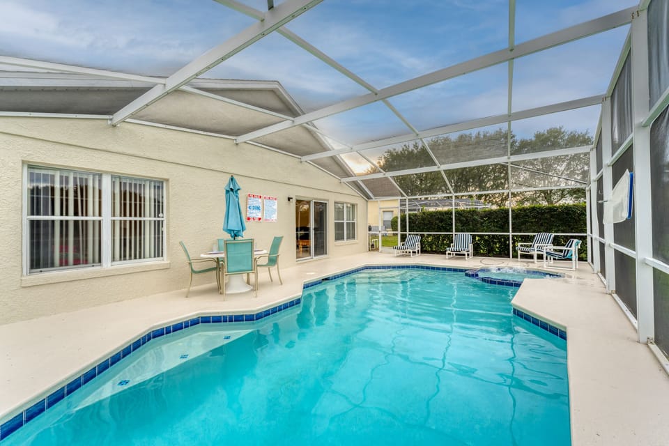 Screened private area with attached spa, patio dining table, lounge chairs, and direct access to the home for easy indoor outdoor living.