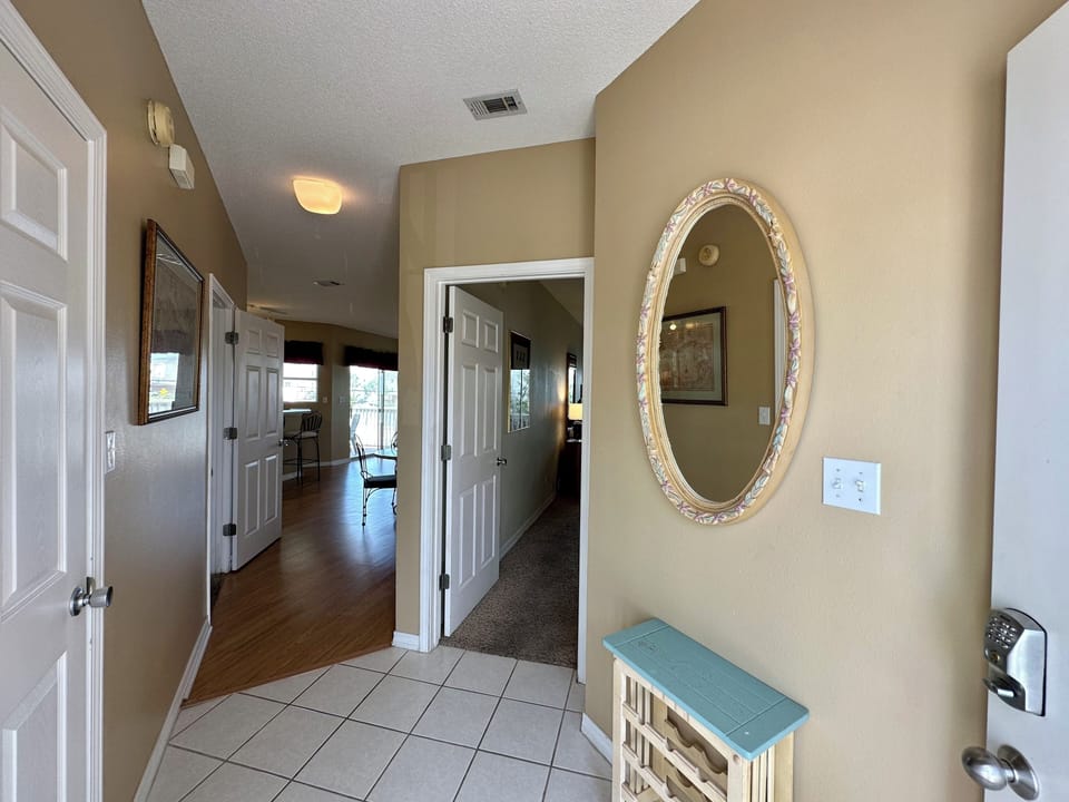 Step into your welcoming entryway featuring warm neutral tones, decorative mirrors, and polished tile flooring that flows into spacious living areas beyond.