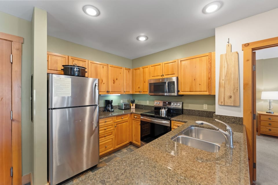 Your fully equipped kitchen features granite countertops, stainless steel appliances, and warm wood cabinets perfect for preparing memorable meals together.
