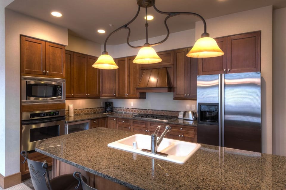 Your gourmet kitchen awaits with granite counters, stainless appliances, and warm pendant lighting for memorable meal preparation.