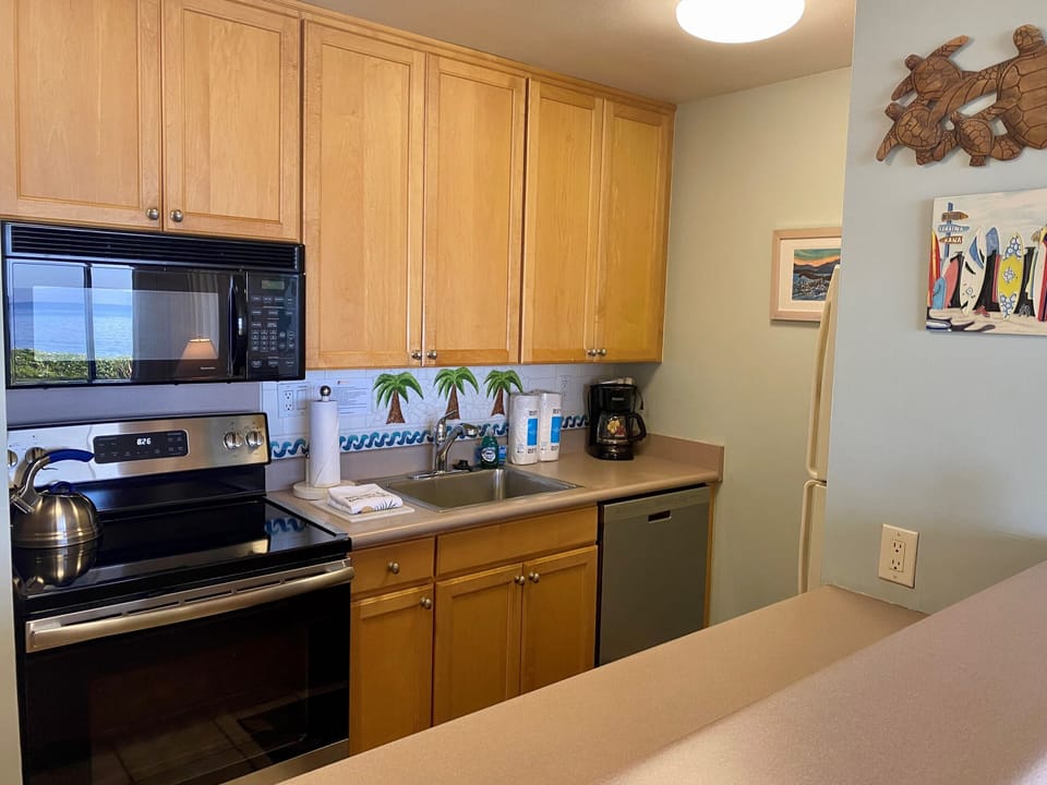 Your fully-equipped kitchen invites you to prepare delicious meals with ocean views and playful coastal decor—turtles and palm trees set a cheerful, beachy vibe as you cook.