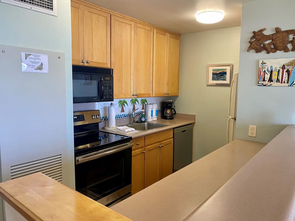 Your fully equipped kitchen features warm wood cabinetry, modern appliances, and thoughtful coastal touches—perfect for preparing fresh meals during your beach getaway.