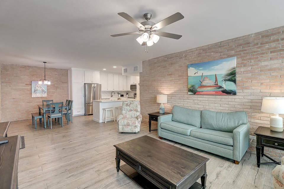 Relax in your spacious open-plan living space featuring modern coastal décor, comfortable seating, and a fully equipped kitchen for memorable meals together.