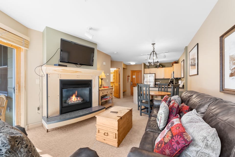 Cozy up by your crackling fireplace while watching TV from the plush sofa, with colorful pillows adding warmth to your mountain retreat.