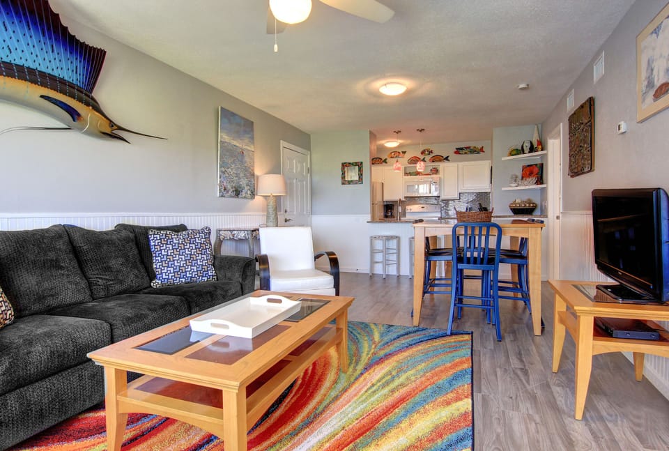 Relax in your bright, open living space with comfortable seating, modern kitchen, and coastal-inspired touches creating the perfect home base.