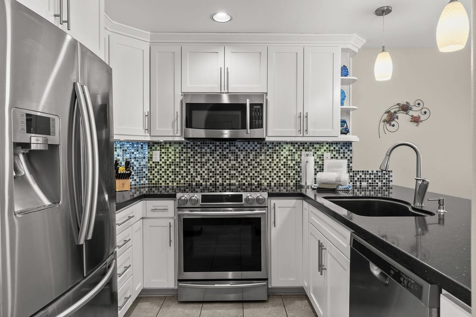 Cook your favorite meals in this modern kitchen with stainless steel appliances, granite counters, and colorful mosaic backsplash.