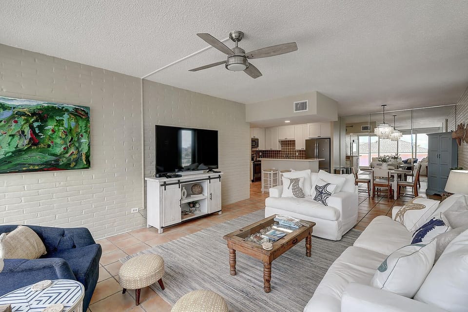 Relax in your spacious living room featuring comfortable seating, modern entertainment center, and open-concept design flowing into your fully equipped kitchen.