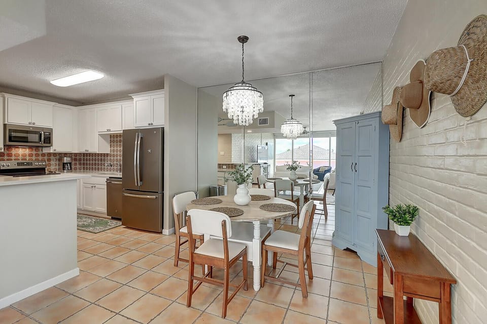 Your open-plan kitchen and dining space features elegant chandeliers, modern appliances, and warm tile floors for memorable meals together.