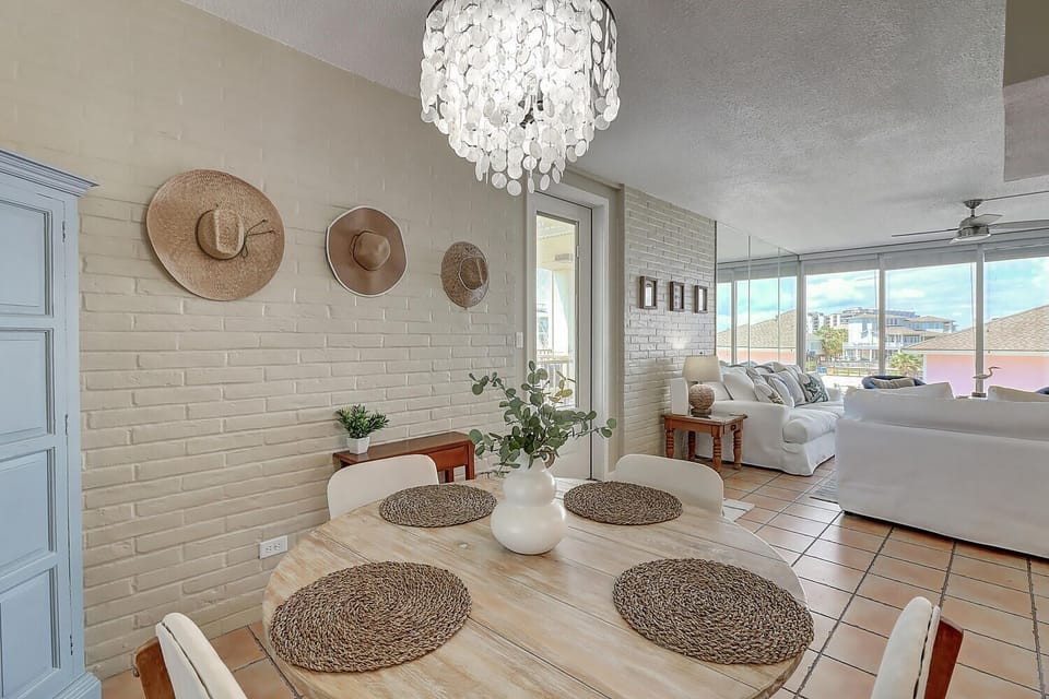 Gather around your bright dining table with coastal charm, where white brick walls and woven placemats create the perfect setting for shared meals.