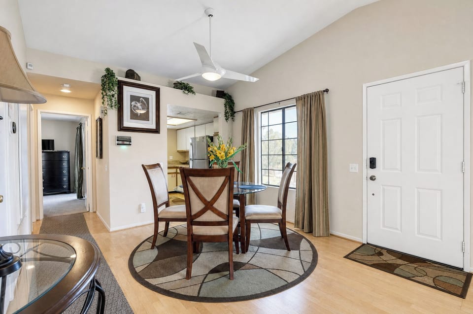 Gather around this inviting dining table, where natural light streams through large windows and a modern ceiling fan keeps you comfortable during meals together.