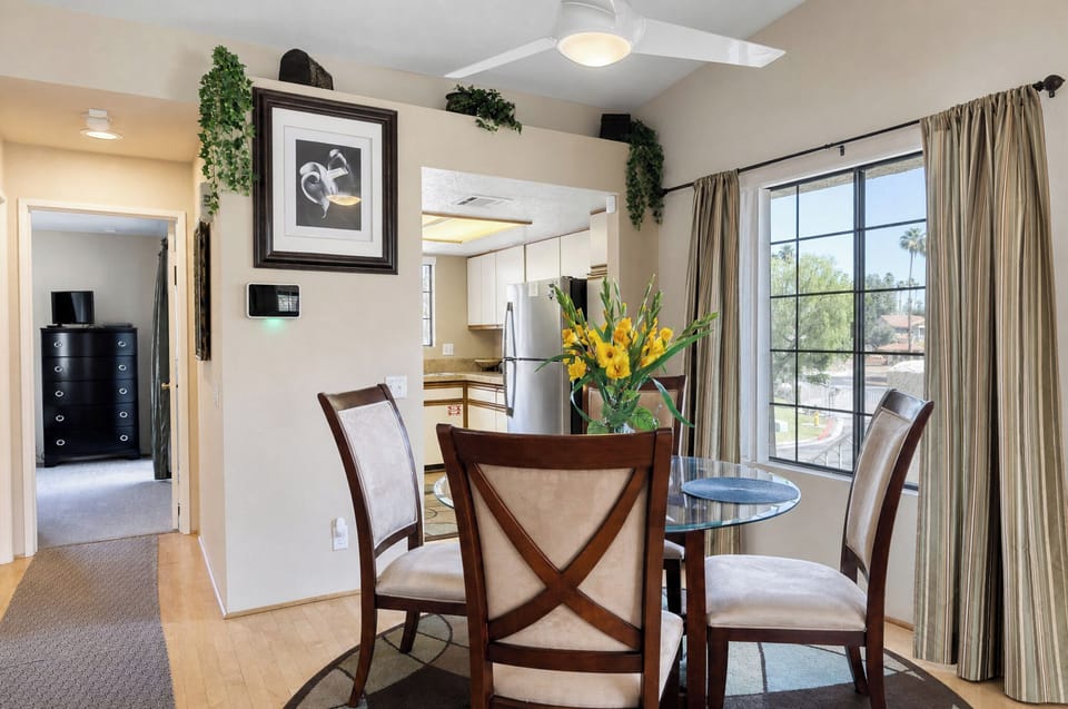 Gather around this inviting dining table, where natural light pours through expansive windows. Fresh flowers brighten your meals, and a fully equipped kitchen is steps away for easy entertaining.