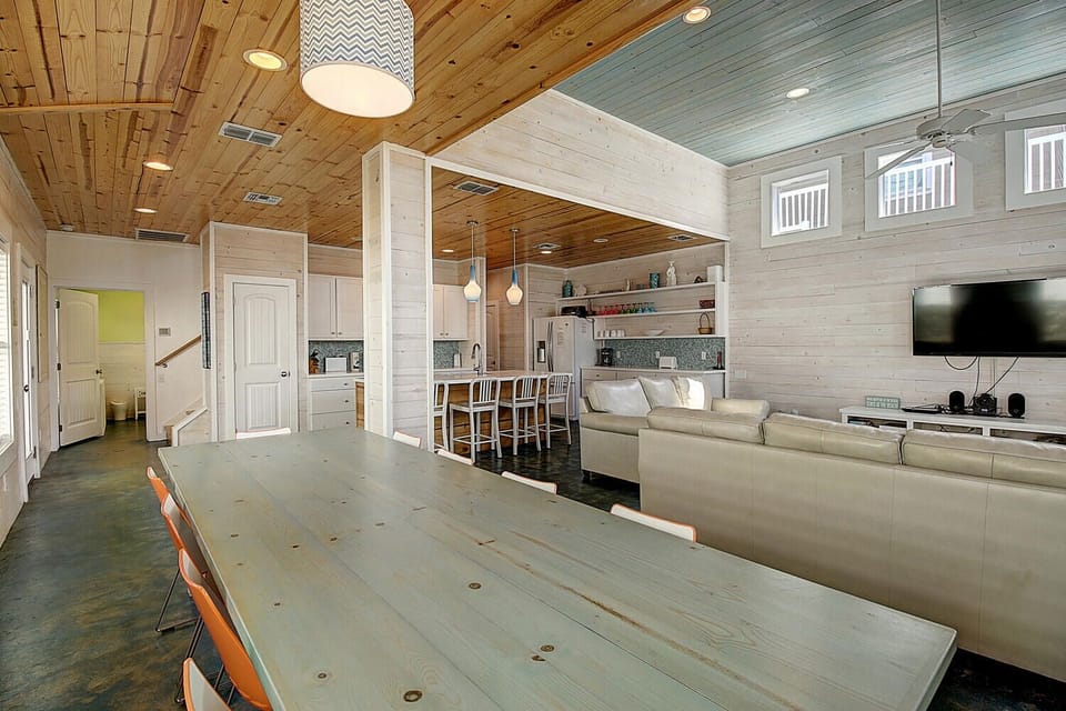 Gather with friends in your spacious open-plan living space, featuring warm wood ceilings and a stylish kitchen island for memorable meals together.