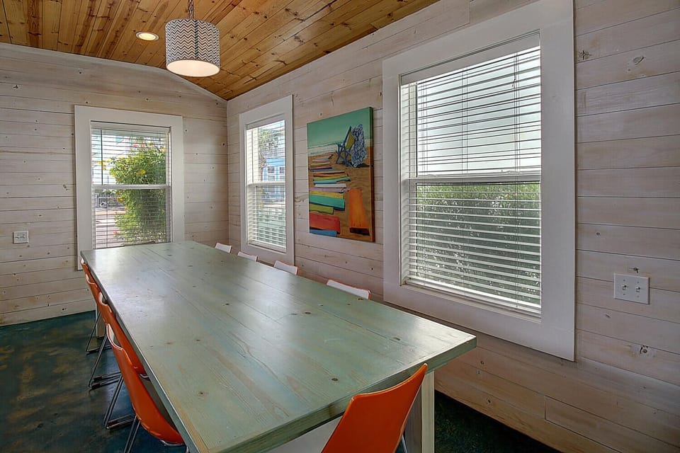 Your spacious dining room features warm wood walls, vibrant orange chairs, and abundant natural light for memorable meals together.
