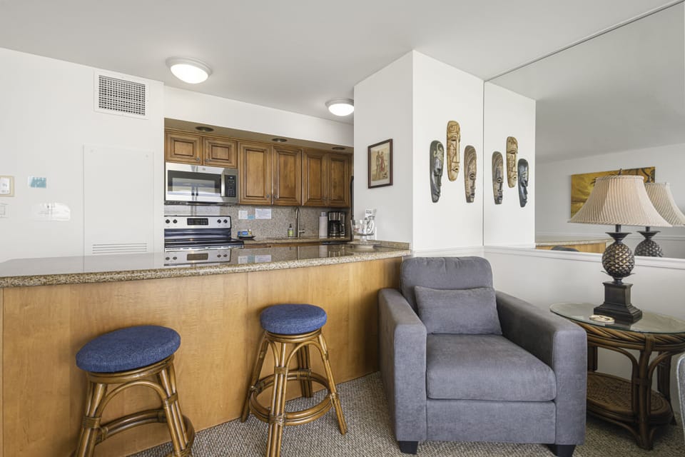 Unwind in your open living space with a well-equipped kitchen and cozy seating, perfect for relaxing after a day of exploring the island. Tropical touches bring warmth to this inviting retreat.