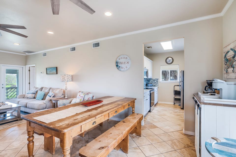 Gather around your rustic wooden dining table, where exposed ceiling beams create coastal charm in this open kitchen-living space.