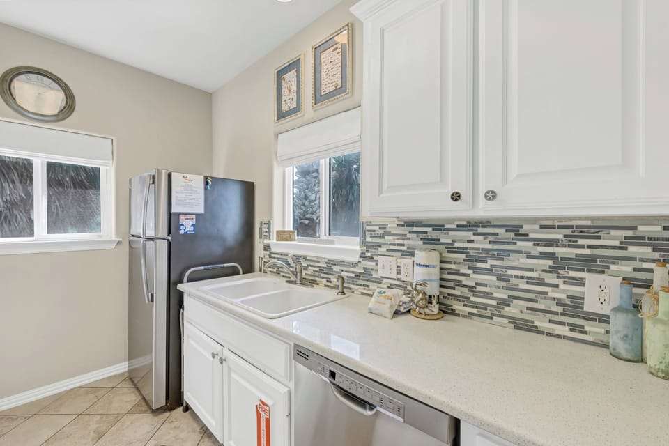 Step into your bright, well-appointed kitchen featuring sleek white cabinets, elegant mosaic backsplash, and modern stainless appliances for effortless meal preparation.