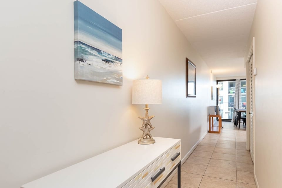 This welcoming hallway features a stylish console table, artwork, and leads to a bright seating area with a lovely view