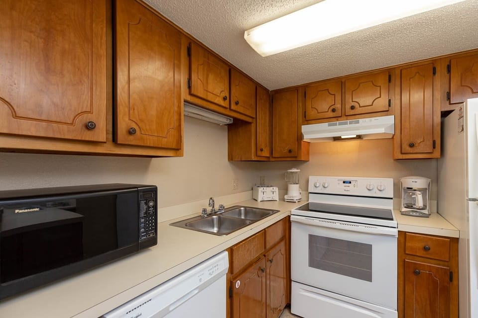 This kitchen features warm wood cabinetry, essential appliances, and ample counter space for meal preparation