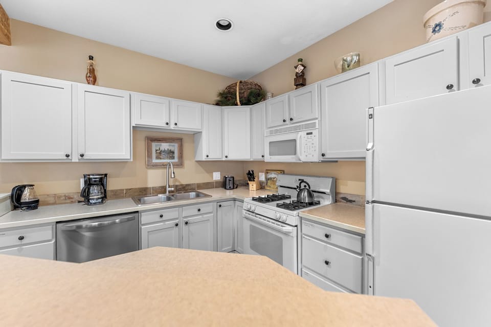 Your fully equipped kitchen awaits with modern appliances and warm white cabinetry, perfect for creating memorable meals during your stay.