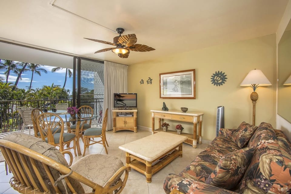 Relax in your spacious tropical living room with island-inspired décor, comfortable seating, and a breezy lanai opening to swaying palms and ocean views just beyond.