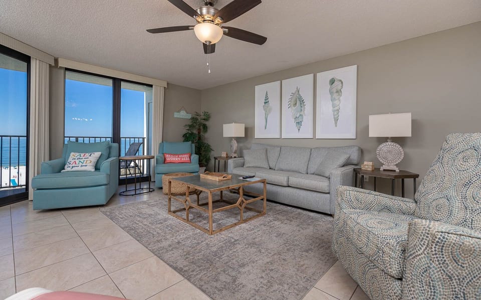 Cozy living area features a light gray sofa with queen sleeper, vibrant accent chairs, and a balcony with a beautiful view