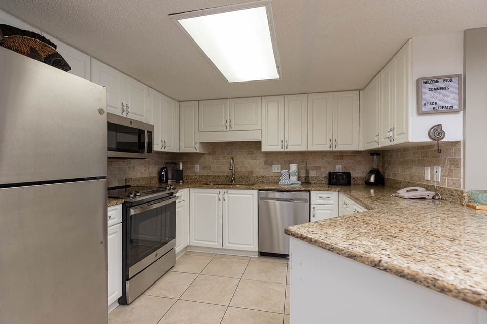 Bright kitchen with granite countertops, white cabinetry, and modern appliances, perfect for preparing meals during your stay