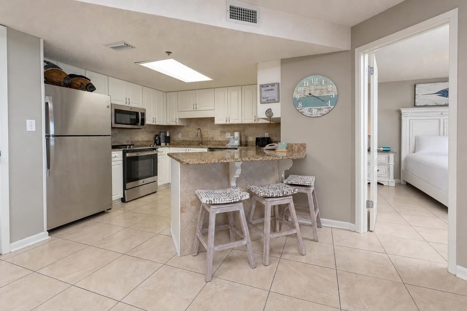 Bright kitchen area features granite countertops, stainless appliances, and a breakfast bar with seating