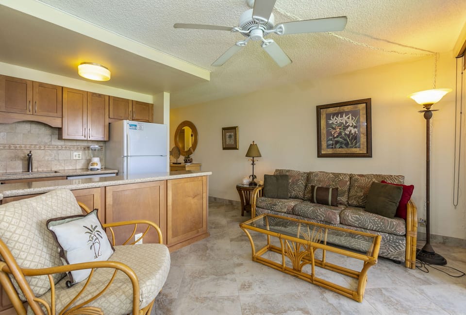 Unwind in your open-concept living space where the fully equipped kitchen flows seamlessly into a cozy lounge area with island-inspired furnishings and ceiling fan for your comfort.