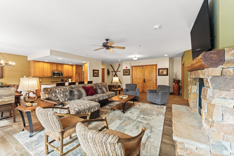 Unwind in your spacious living room where rustic charm meets modern comfort, featuring a cozy stone fireplace perfect for mountain evenings.